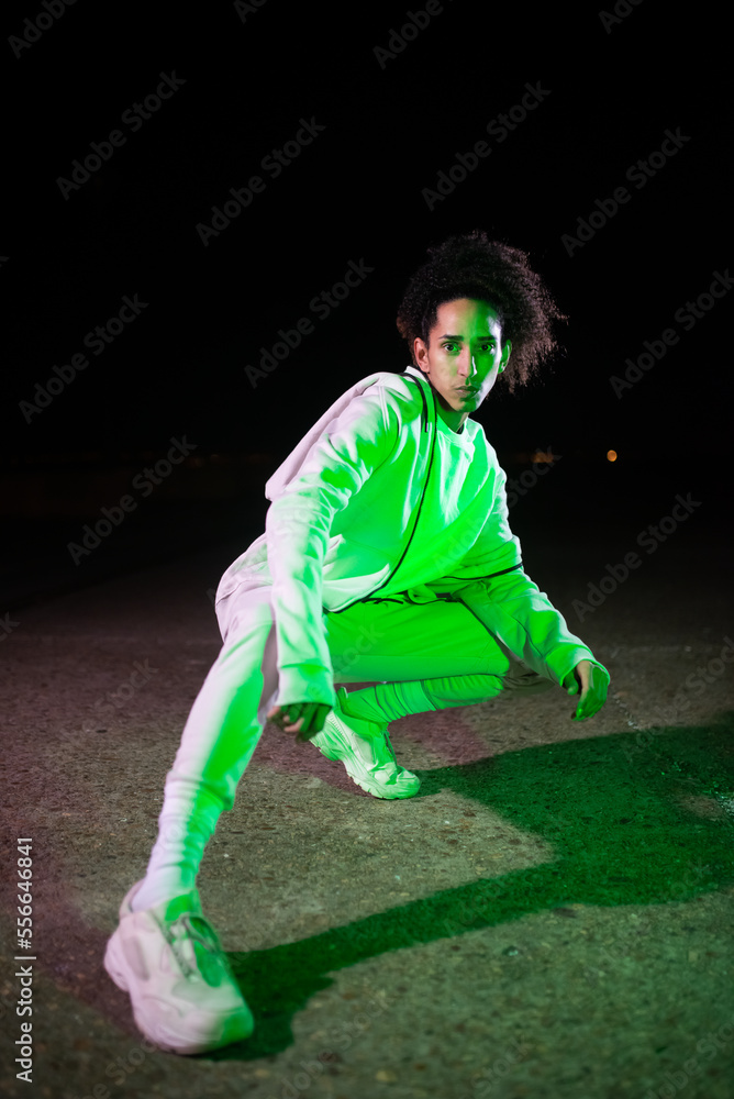 Good-looking male dancer at night. Man in modern clothes looking at camera and standing in dancing pose. Dancing, hobby concept Good-looking male dancer at night. Man in modern clothes looking at camera and standing in dancing pose. Dancing, hobby concept