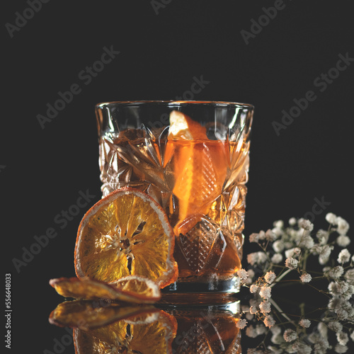 Citrus alcoholic cocktail in a glass. Alcoholic drink decorated decorated with citrus slices and dried flowers. Dark background. Copy space. Side view. 
