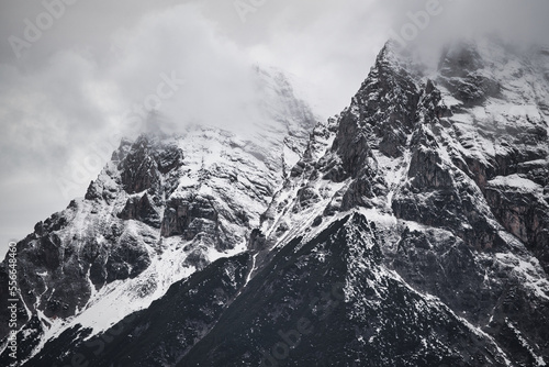 Dreamy mysterious winter landscape with fog and snow covered mountains and clouds in the sky