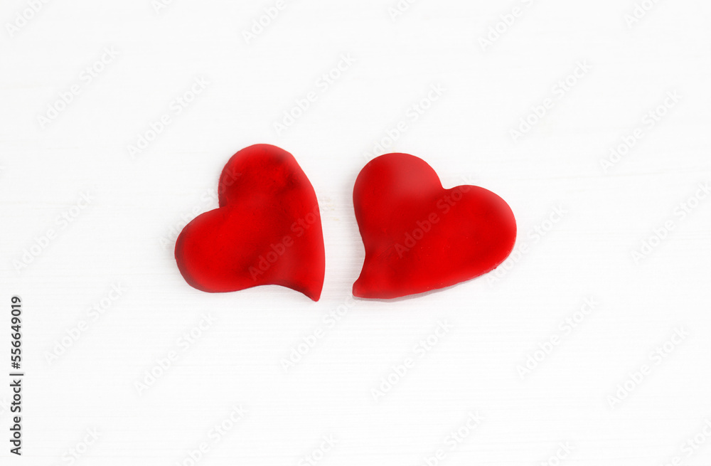 kid playing with plasticine clay making colorful hearts or holding one red heart at mouth.happy or sad upset emoticon made by child preschooler pointing with index finger.valentine day love february