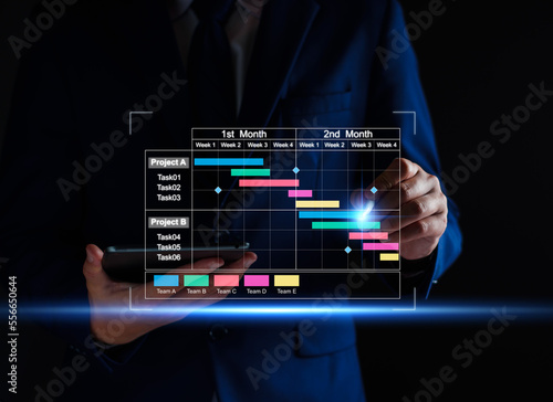 Project manager working on tablet and updating tasks and milestones progress planning with Gantt chart scheduling interface for company on virtual screen. Business Project Management System.