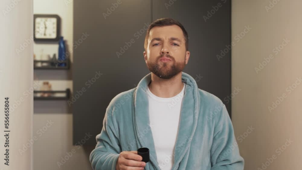 A handsome man in a bath robe put a special product in his mouth A handsome man in a bath robe put a special product in his mouth