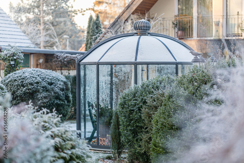 Perspektivischer Blick auf runden Wintergarten in schön gestaltetem Garten im Winter