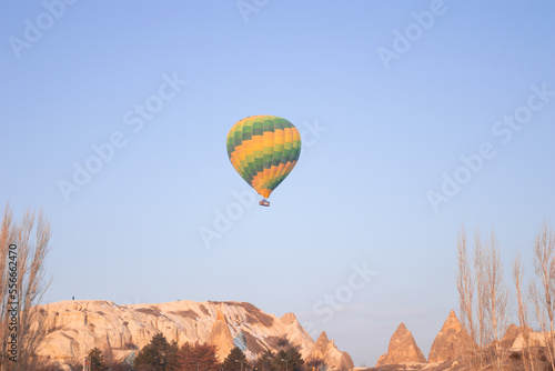A bright green hot air balloon flying over the mountains landscape