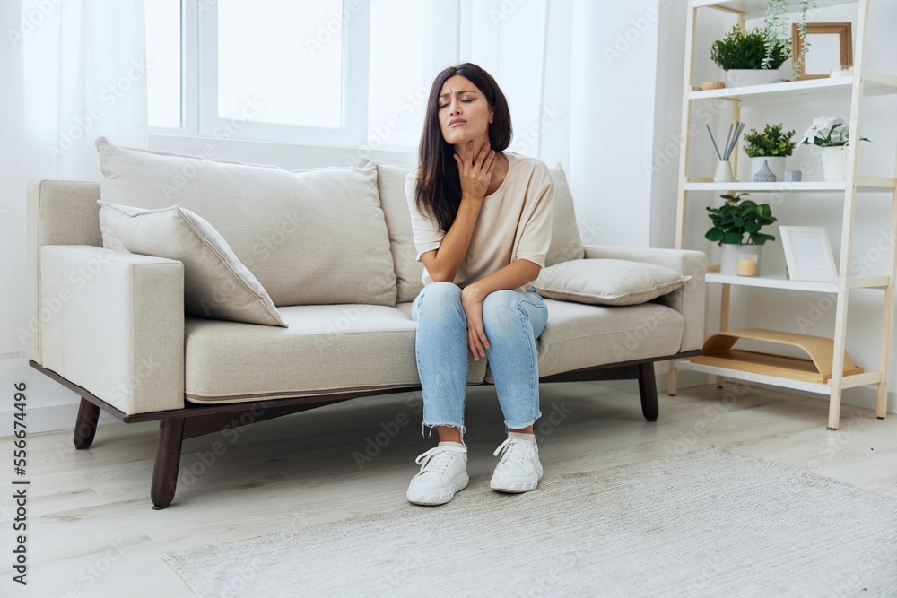 Woman sitting on sofa at home pain in nose and throat, cold and allergy, covid-19 disease, temperature Woman sitting on sofa at home pain in nose and throat, cold and allergy, covid-19 disease, temperature
