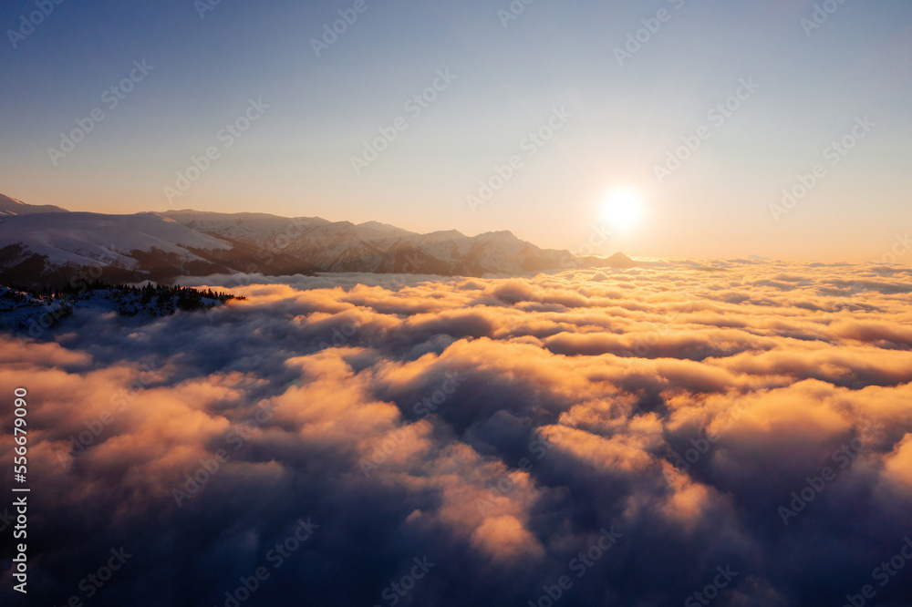 Caucasian mountains above the clouds at the sunset. Cloudscape, aerial view