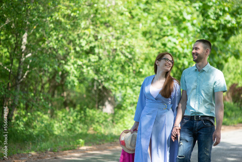 young family, married couple, man and woman walking in the park on a sunny summer day