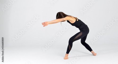 Fototapeta Naklejka Na Ścianę i Meble -  Young sporty yogi woman practicing yoga, doing Wild Thing, pose, working out, wearing sportswear, black pants and top, indoor full length, white yoga studio 