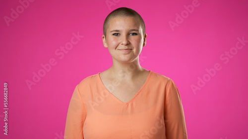 Smiling young gender fluid woman 20s years old posing isolated on pink background studio. People sincere emotions lifestyle concept. Looking at camera with charming smile © Robert Peak