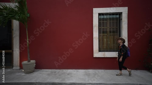 Pretty, mature, woman walking on a sidewalk along colorful buildings in Merida, Yucatan, Mexico. photo
