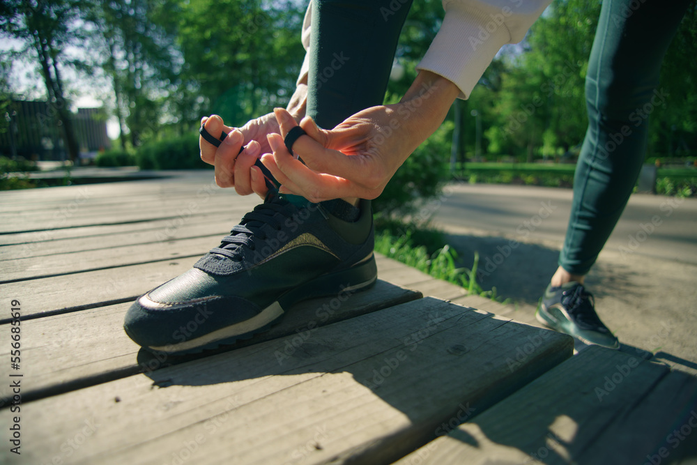 Obraz premium Woman hands to tie their shoes jogging in morning workout at the city, closeup shot