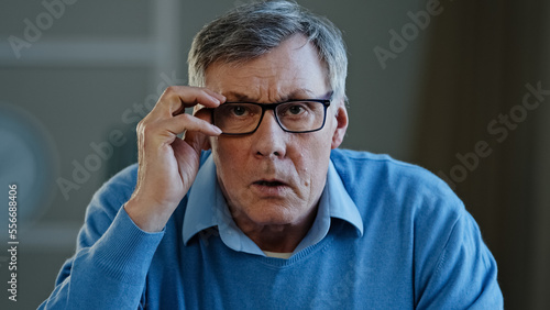 Close up portrait shocked old Caucasian businessman stressed upset man elderly 60s male worried holding head with shock fear take off eyeglasses looking at camera failure lost job unexpected bad news