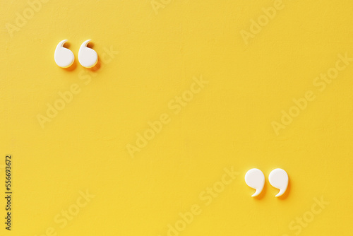 Quotation mark with copy space on yellow background, White quotation mark on yellow wall 3d illustration. photo