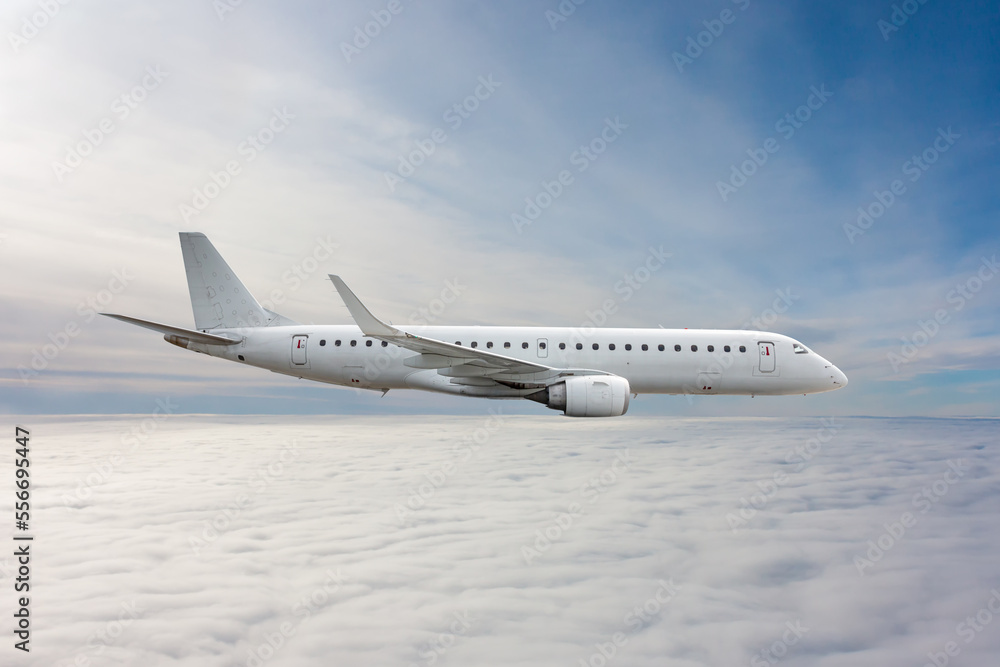 White passenger jet plane flies in the air above the clouds