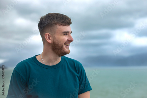 Profile side photo of handsome happy guy, young man enjoying sea, ocean view, landscape, looking into distance at summer day in tropical country at storm with cloudy sky, breathing deep fresh air