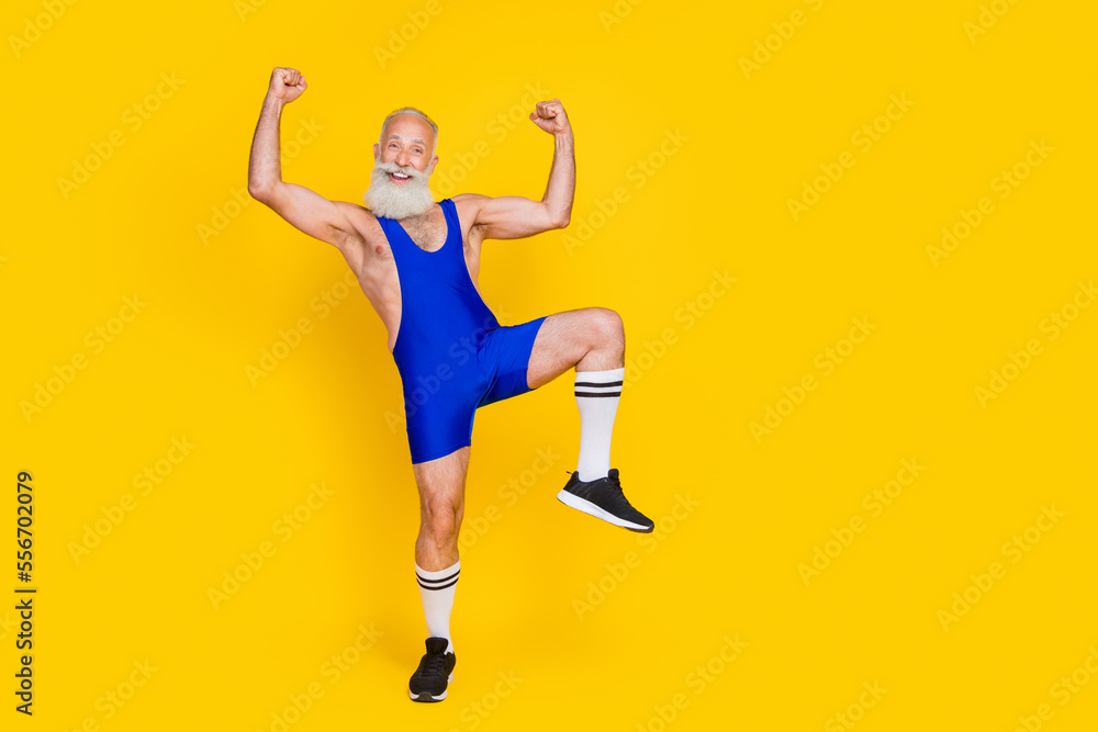 Full length photo of cheerful positive senior guy wear blue overall costume rising fists empty space isolated yellow color background