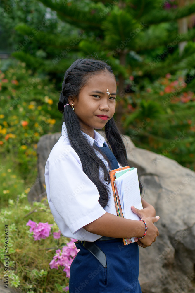 Portrait of a schoolgirl with long ponytails standing in the garden and holding a script Portrait of a schoolgirl with long ponytails standing in the garden and holding a script