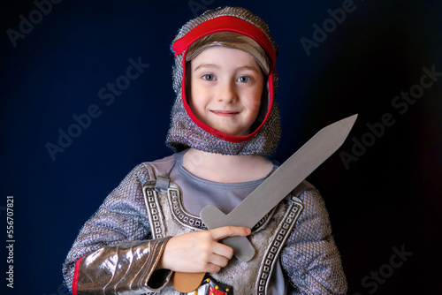 Portrait of a little beautiful boy dressed as a medieval knight with a sword. A child in a knight's costume. Festival, costume party for kids. photo