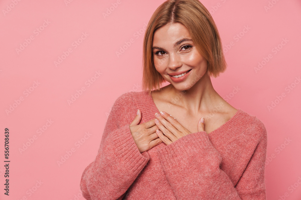 Lovely woman smiling and holding her hands on chest isolated over pink background Lovely woman smiling and holding her hands on chest isolated over pink background
