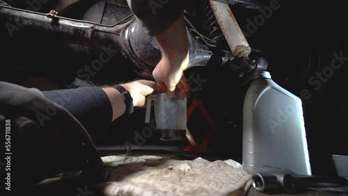 Drains old, used oil in the front differential of an off-road vehicle, truck with four-wheel drive. Car service. Tools and spare parts. Male hands, mechanic. View from the first person	
