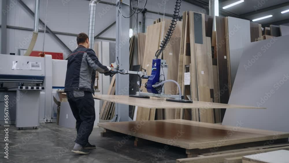 process of loading big details into automated woodworking machine use vacuum lifter, worker in plant process of loading big details into automated woodworking machine use vacuum lifter, worker in plant