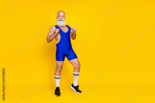 Fototapeta Naklejka Na Ścianę i Meble -  Full length portrait of positive cheerful aged person hands pull stretch uniform isolated on yellow color background