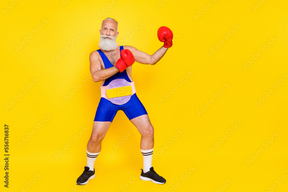 Full body portrait of confident successful grandfather wear boxing gloves champion belt isolated on yellow color background