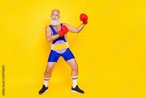 Fototapeta Naklejka Na Ścianę i Meble -  Full body portrait of confident successful grandfather wear boxing gloves champion belt isolated on yellow color background
