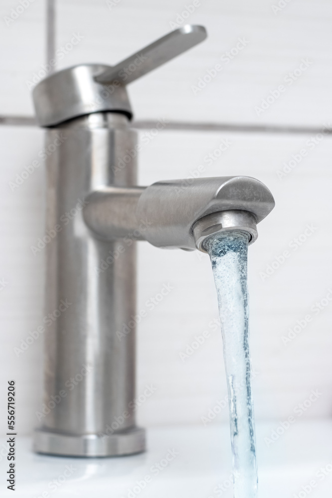 Water flows from the faucet in the bathroom. Water faucet close-up. Saving water. The faucet needs repair Water flows from the faucet in the bathroom. Water faucet close-up. Saving water. The faucet needs repair