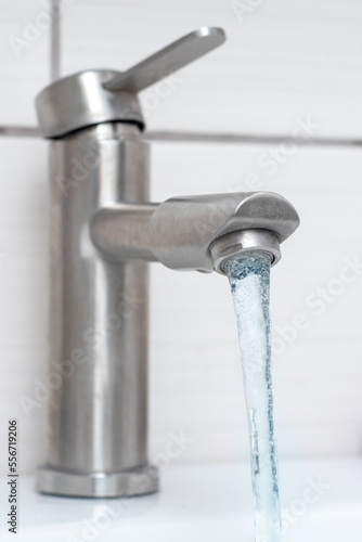 Water flows from the faucet in the bathroom. Water faucet close-up. Saving water. The faucet needs repair