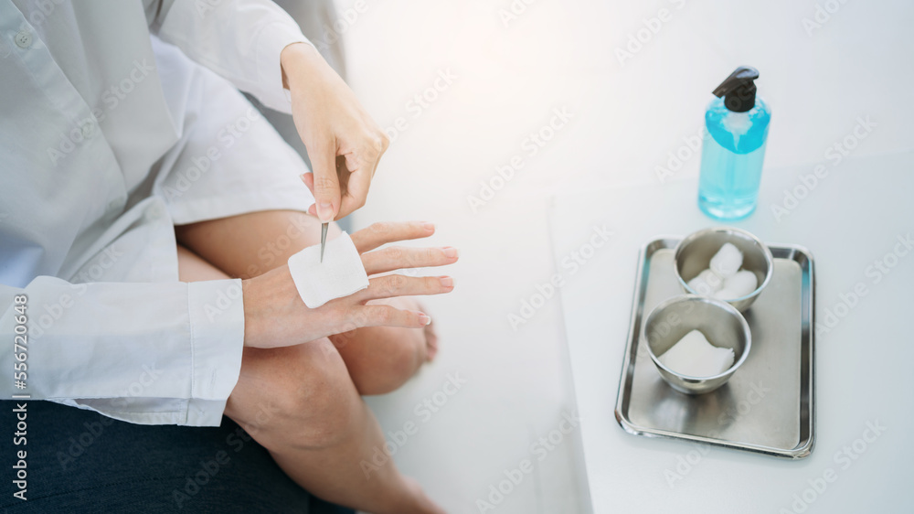 After sustaining an injury in an accident, a woman performs self-healing procedures on the wound using a cotton ball and a dressing set. After sustaining an injury in an accident, a woman performs self-healing procedures on the wound using a cotton ball and a dressing set.