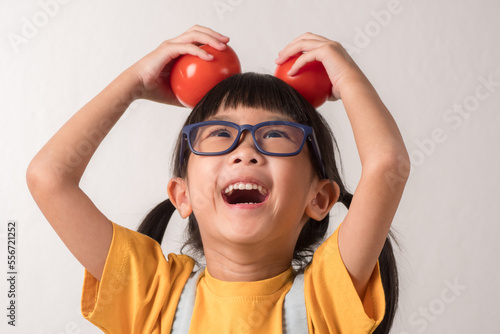 Kid happy with eating vegetable. Cute girl has fun with tomatoes.