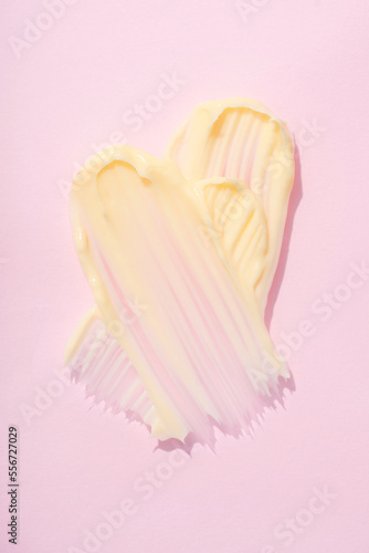 Vertical image of silky cosmetic cream texture. Cream or body butter smears over pink background. Skincare product