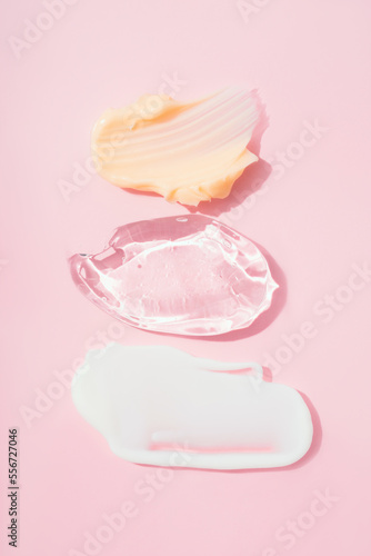 Set of cream and gel smears, various cosmetic products texture. Cream and gel smudges over pastel pink background. Skincare and beauty product. Vertical image