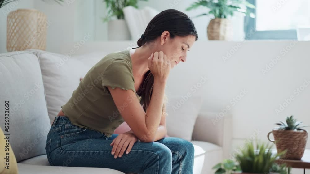 Video of worried woman thinking about problems while sitting on couch in the living room at home. Video of worried woman thinking about problems while sitting on couch in the living room at home.