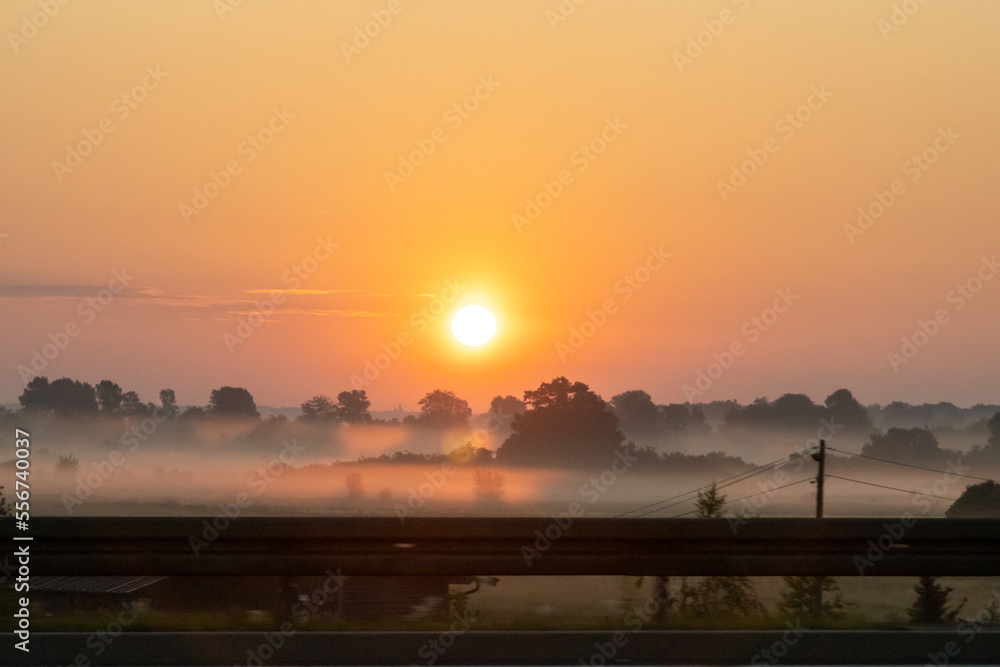 The morning sun rises above the fog as seen from the highway in Kiev