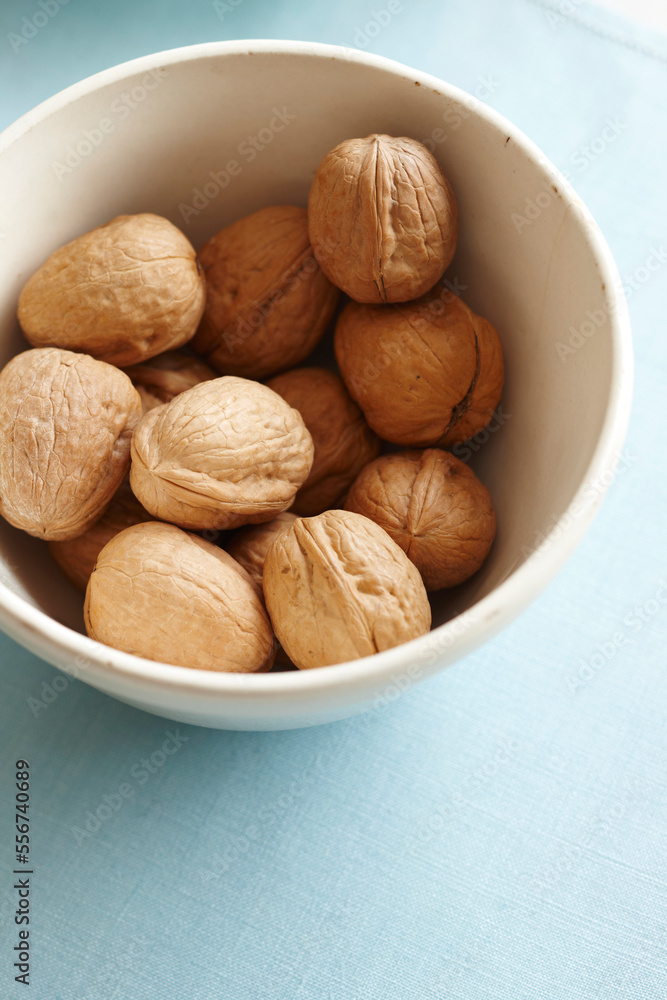 whole walnuts in the shell in a bowl on a blue fabric whole walnuts in the shell in a bowl on a blue fabric