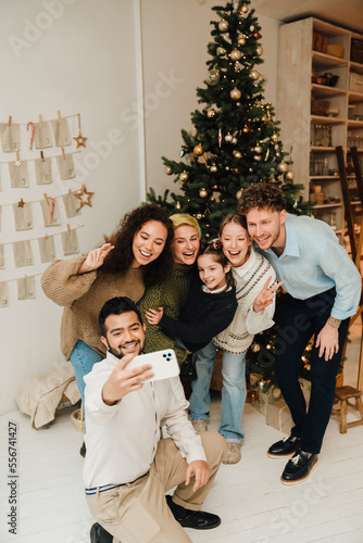 Cheerful family taking selfie while standing together near Christmas tree © Drobot Dean