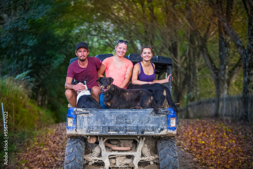 Three young adults sit in the back of a dune buggy with dogs after a muddy tour; Retaruke, Manawatu-Wanganui, New Zealand