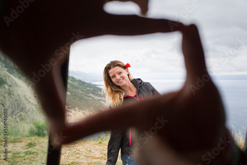 Framing a beautiful girl with fingertips with the Croatian coastline in the background; Pisak, Splitsko-dalmatinska zupanija, Croatia photo