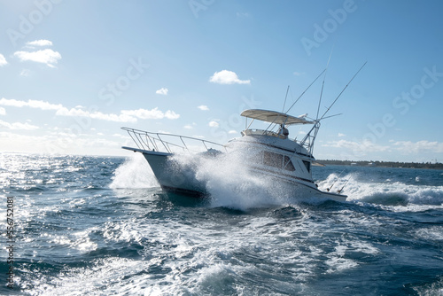 Yacht speeding through the wavy water off the coast of Punta Cana on a deep sea fishing excursion; Punta Cana, La Altagracia, Dominican Republic photo