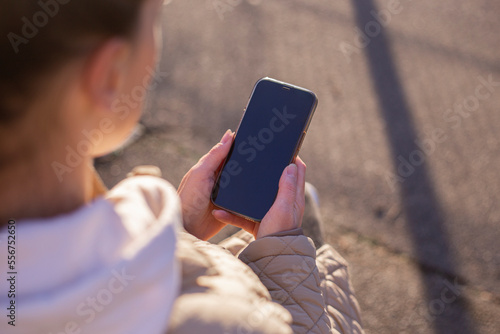 Young woman's face is not visible holding the phone in the street