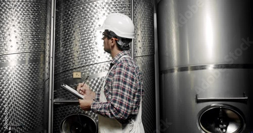 Large steel barrels for wine fermentation. Wine production plant. Steel wine distilling tanks. Winemaker looking equipment for distillation and fermentation at wine factory.