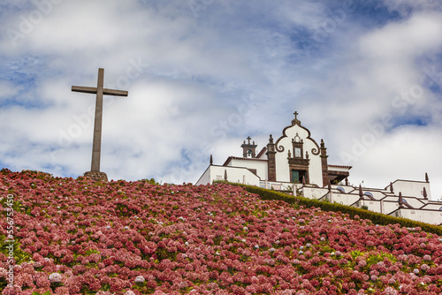 Cross and blossoming flowers on a hillside at Hermitage of Nossa Senhora da Paz; Soa Miguel, Azores, Portugal photo