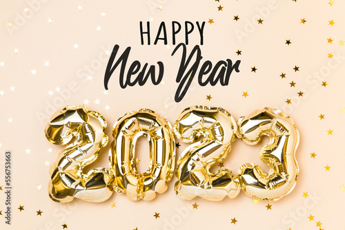 New year 2023 balloon celebration card. Gold foil helium balloon number 2023 and Happy New Year lettering on beige background. Flat lay, merry christmas, happy holidays congratulation
