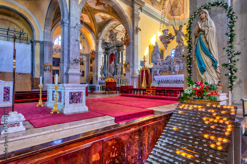 Interior of the Church of St Euphemia, showing a religious statue and candles lit for prayers and intentions with an elaborate main altar in the background; Rovinj, Istria, Croatia photo