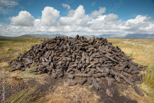 Turf cut and stacked in a pile of peat bricks along the Bog Road (Bothar na Scrathog) in Connemara; Carraroe, County Galway, Ireland photo