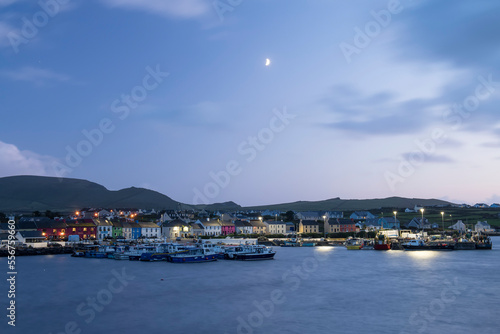 The small town of Portmagee and harbor at dusk with the quarter moon in the sky; Portmagee, County Kerry, Ireland
