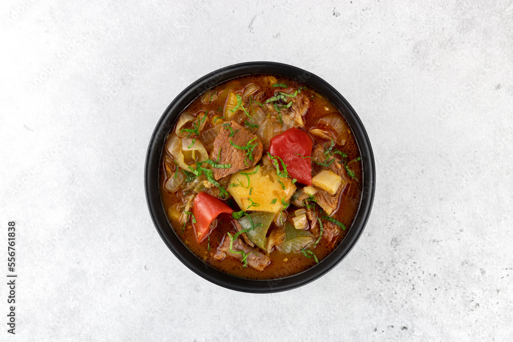 Khashlama stew of beef or lamb meat with vegetables on a black plate, top view. Armenian and Georgian cuisine.