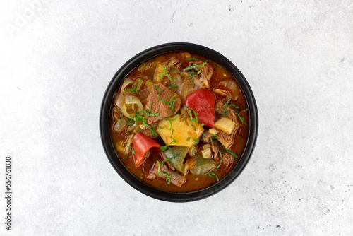 Khashlama stew of beef or lamb meat with vegetables on a black plate, top view. Armenian and Georgian cuisine.